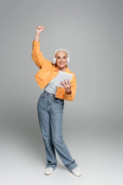 Joyful Senior Woman Headphones Holding Digital Tablet Showing Win Gesture — Stock Photo, Image