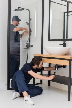 plumbers in uniform working together in bathroom clipart