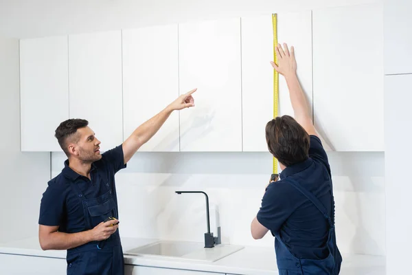 Workman Pointing Colleague Measuring Furniture Cabinets Kitchen — Stock Photo, Image