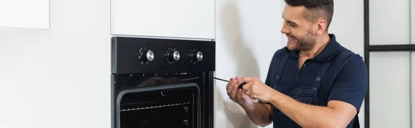 Happy Handyman Repairing Electric Inbuilt Oven Modern Kitchen Banner — Stock Photo, Image