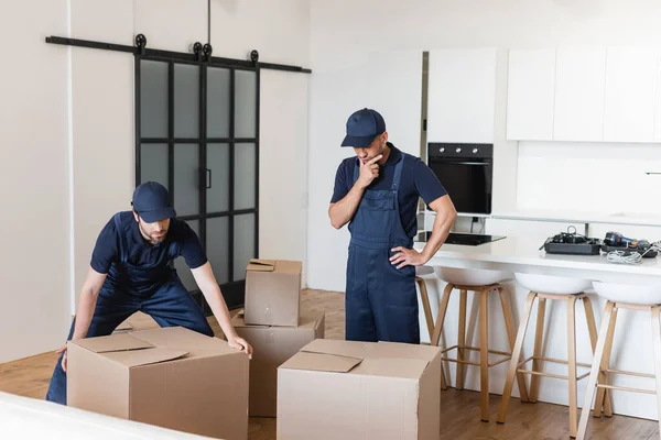 Trabajador Reflexivo Pie Con Mano Cadera Cerca Colega Cajas Cartón — Foto de Stock