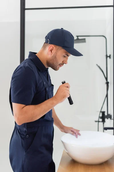 Seitenansicht Des Klempners Mit Taschenlampe Der Nähe Waschbecken Modernen Badezimmer — Stockfoto