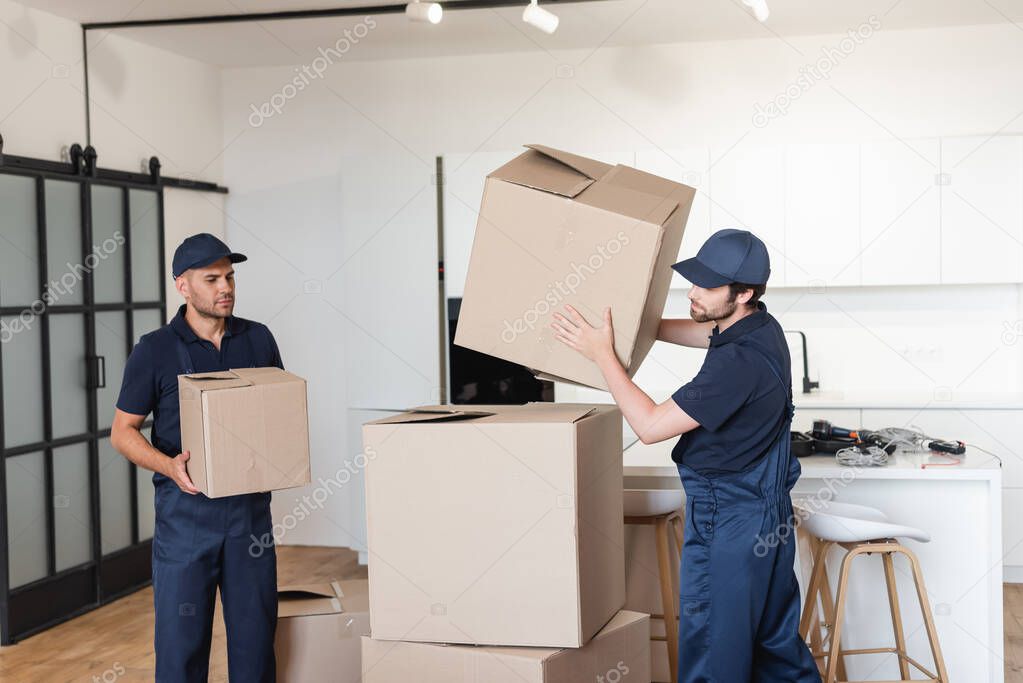 workers in uniform stacking carton packages in kitchen