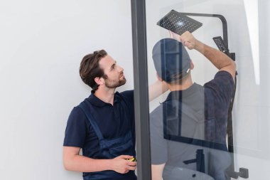 plumbers checking shower head with flashlight clipart