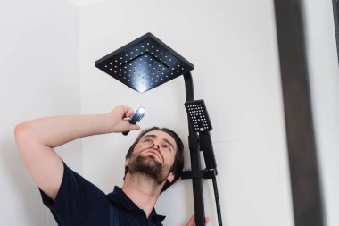 low angle view of plumber lighting on shower head in bathroom clipart