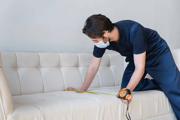 Young Handyman Medical Mask Measuring White Couch — Stock Photo, Image