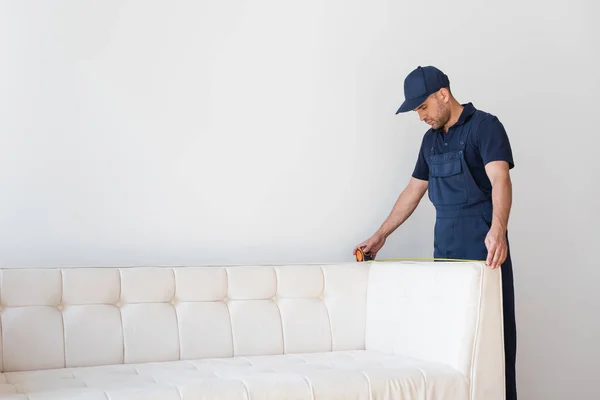 Obrero Con Gorra Mono Que Mide Sofá Moderno Cerca Pared — Foto de Stock