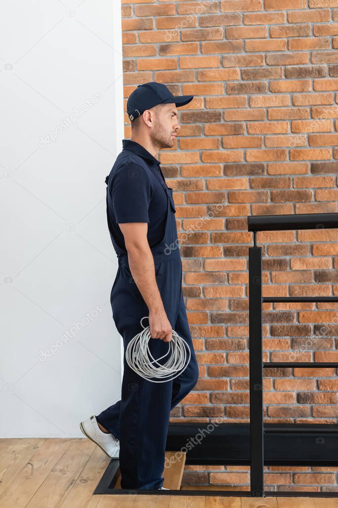 side view of foreman with cable walking downstairs in apartment