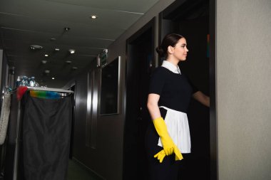 Genç, gülümseyen hizmetçi otel koridorunda kapıyı çalıyor. 