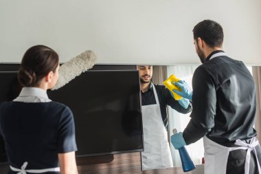 Temizlikçiler otel odasını temizlik malzemeleriyle temizliyor.
