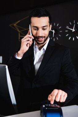Otelde akıllı telefondan konuşan neşeli resepsiyonist.