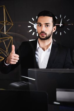Sakallı resepsiyonist resepsiyonda baş parmağını gösteriyor. 