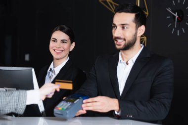 Kredi kartıyla ödeme yapan turistlere bakan mutlu resepsiyonistler. 