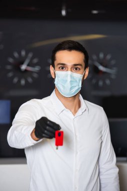Tıbbi maskeli resepsiyonist odasının anahtarını tutuyor. 