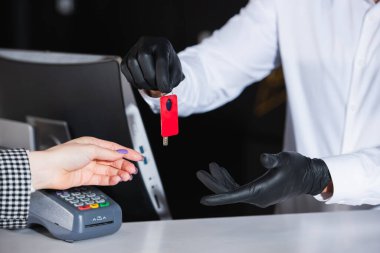 Lastik eldivenli resepsiyonist, misafirlere oda anahtarı veriyor. 