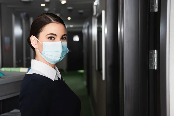 Joven Sirvienta Uniforme Máscara Médica Mirando Cámara —  Fotos de Stock