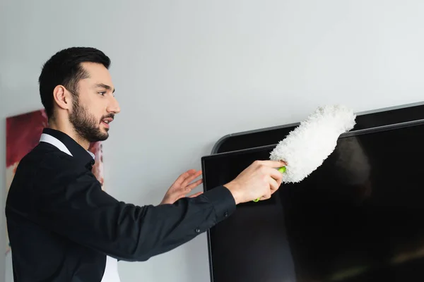 Toz Fırçasıyla Televizyon Temizleyen Sakallı Temizlikçinin Yan Görüntüsü — Stok fotoğraf