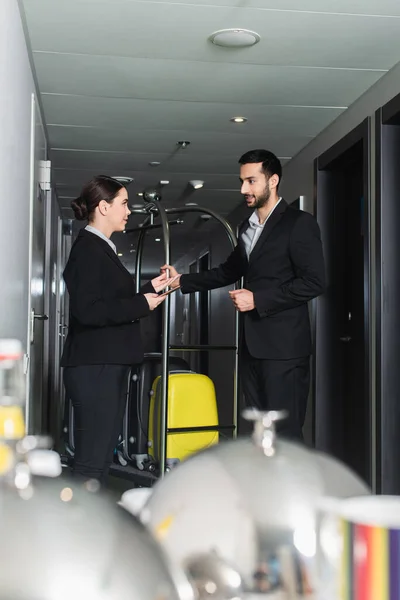 Recepcionista Sosteniendo Smartphone Hablando Con Botones Con Carrito Equipaje — Foto de Stock