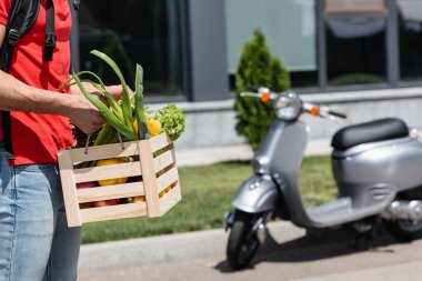 Dağıtımcı elinde tahta kutu ve taze sebzelerle açık havada mobiletin yanında... 