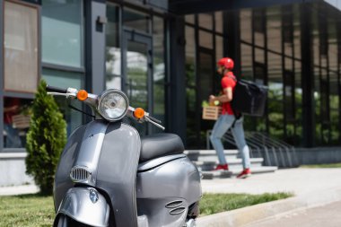 Scooter, teslimatçıyı ve açık hava binasını bulanıklaştırdı.