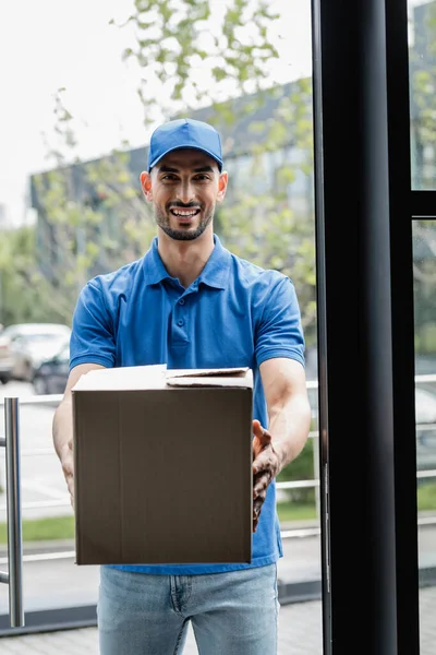 Sorrindo Mensageiro Muçulmano Segurando Caixa Papelão Perto Porta — Fotografia de Stock