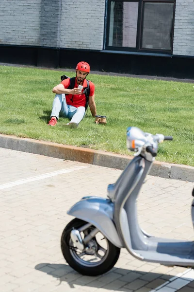 Corriere Arabo Utilizzando Smartphone Vicino Caffè Andare Erba Scooter Sfocato — Foto Stock