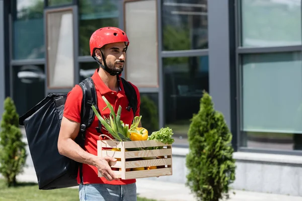 Muslim Deliveryman Protective Helmet Carrying Fresh Vegetables Outdoors — Stock Photo, Image