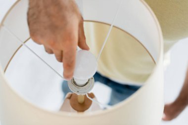 Lambanın yanında enerji tasarrufu yapan bir adamın kırpılmış görüntüsü.