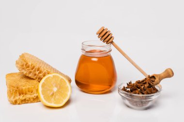 Bal peteği, zencefil kökü ve taze limon, anason tohumlu kase ve beyaz üzerine ahşap kepçeli bal kavanozu.
