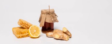 Taze limon, zencefil kökü ve bal peteği ile kaplanmış bal kavanozu beyaz, afiş