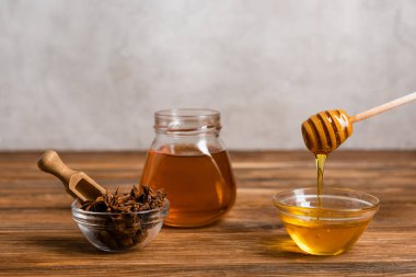Ahşap kaplama ve kavanozun yanında kepçe ve bal ve anason tohumları gri mermer arka planda