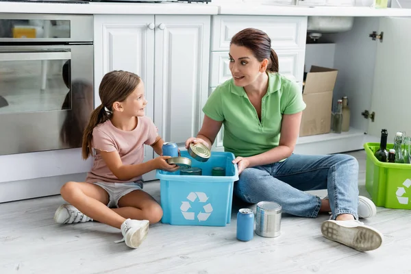Positives Mädchen Steckt Blechdosen Karton Mit Recyclingschild Neben Mutter Küche — Stockfoto