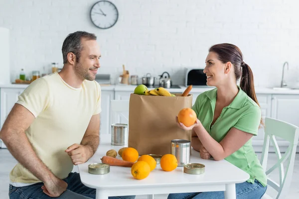 Donna Sorridente Che Tiene Arancione Vicino Cibo Borsa Artigianale Marito — Foto Stock