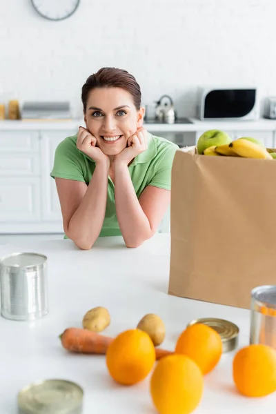 Donna Sorridente Che Guarda Fotocamera Vicino Cibo Sfocato Sacchetto Carta — Foto Stock