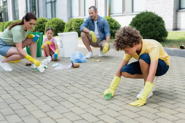 Junge Holt Flasche Aus Dem Boden Bei Verschwommener Familie Freien — Stockfoto