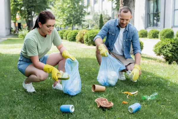 Lächelndes Paar Gummihandschuhen Sammelt Müll Säcken Auf Dem Rasen — Stockfoto