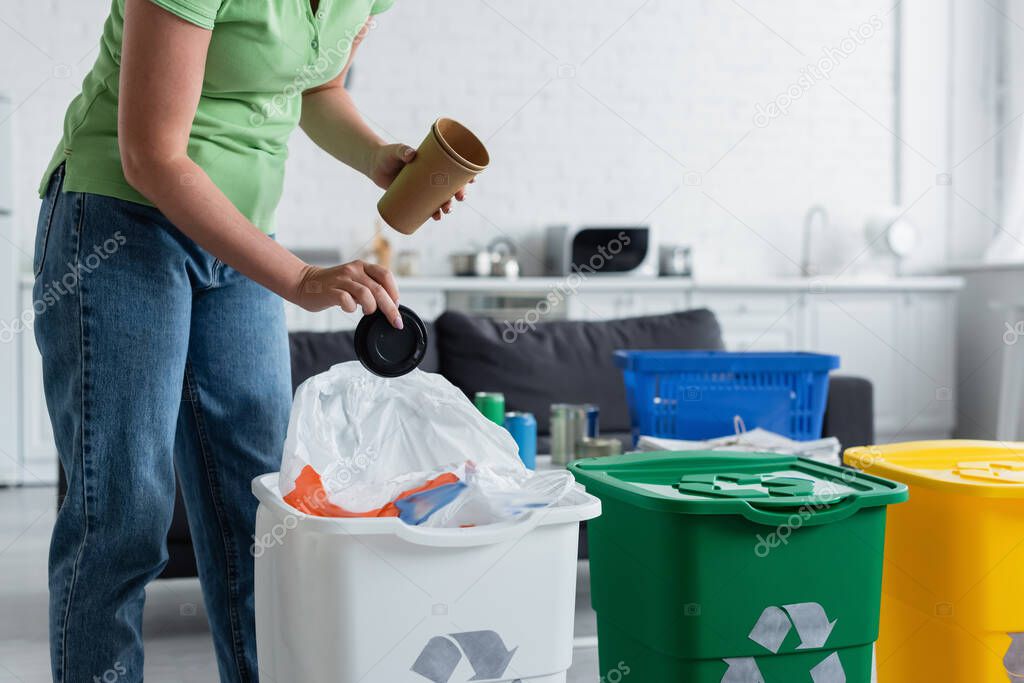 Cropped view of woman holding trash near can with recycling sign in kitchen 