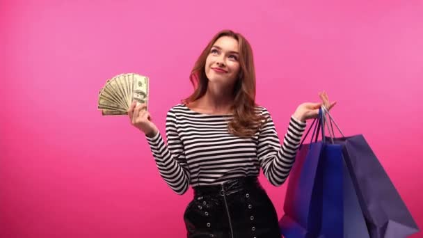 幸せな女性がショッピングバッグやピンクに隔離されたドルを持ち — ストック動画
