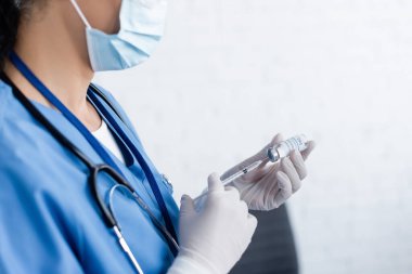 Şırıngayı aşıyla dolduran tıbbi maskeli doktor görüntüsü