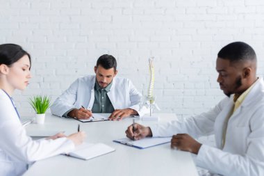 Toplantı odasında evraklarla çalışan çok ırklı doktorlar.