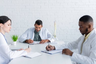 multiethnic doctors working with papers in meeting room clipart