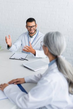 Bulanık orta yaşlı meslektaşımla konuşurken genç doktor el kol hareketi yapıyor.