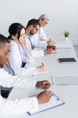  multiethnic doctors working with documents in hospital conference room clipart