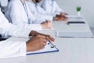 Bulanık çok kültürlü meslektaşların olduğu konferans sırasında panoya yazı yazan hekimin kısmi görünümü 