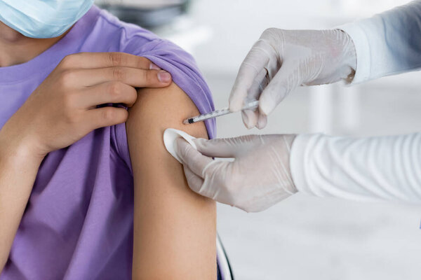 partial view of nurse in latex gloves giving vaccine injection to man