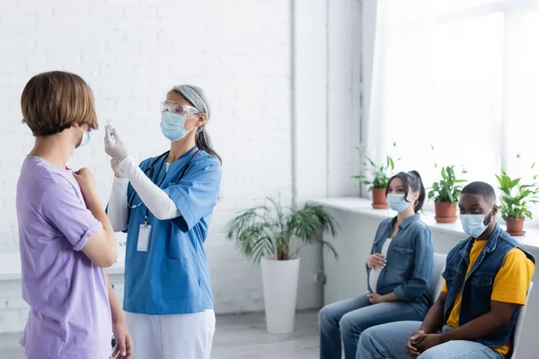 Mogen Asiatisk Läkare Som Håller Burk Med Vaccin Nära Ung — Stockfoto