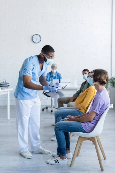 Médico Afroamericano Máscara Médica Sujetando Portapapeles Mientras Habla Con Los — Foto de Stock