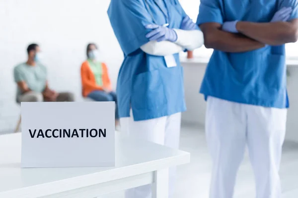 Interracial Physicians Standing Crossed Arms Blurred Patients Vaccination Center — Stock Photo, Image