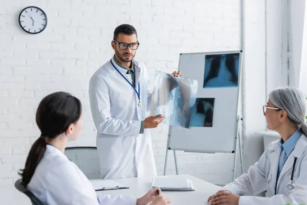 Doctor Anteojos Mostrando Radiografías Pulmonares Colegas Multiétnicos Durante Consejo Médico — Foto de Stock