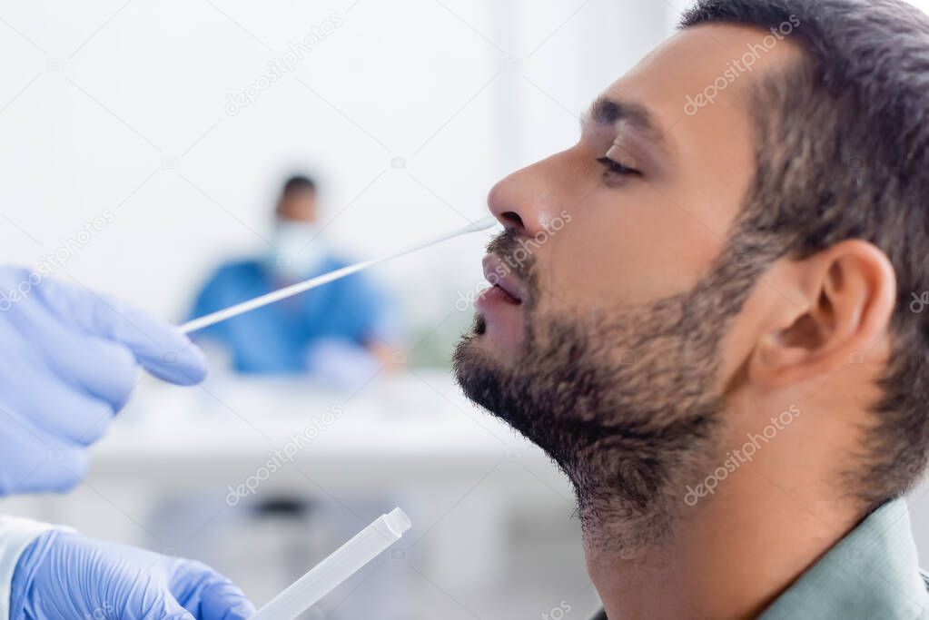 doctor in latex gloves taking samples for coronavirus test from man in hospital